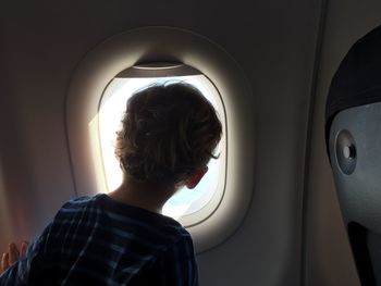 Rear view of boy looking through window