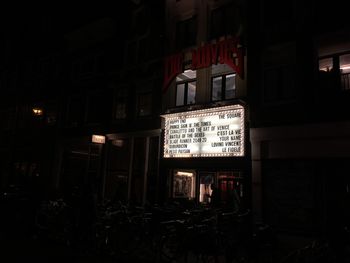 Information sign on street against illuminated building at night