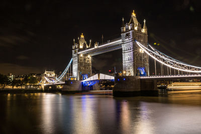 Illuminated bridge over river at night