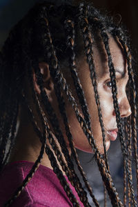 Profile view of one beautiful and attractive brunette young woman head close up looking down with braided hair and gray background