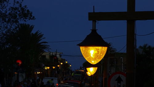 Illuminated street light in city against sky at night