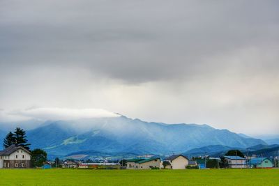 Houses and buildings against sky with mountains in background