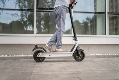 Low section of man riding push scooter on street