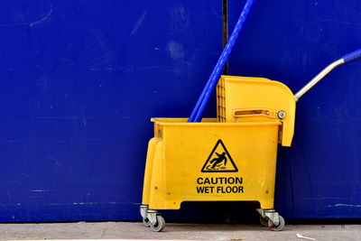 Yellow mop bucket on blue wall