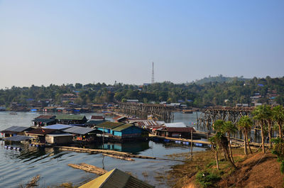 Boats moored in river by buildings against clear sky