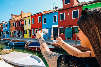 Reflection of woman on boat in canal against buildings in city