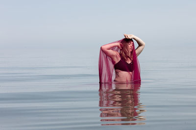 Woman in pink sea against sky