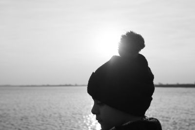 Rear view of boy wearing warm clothing against sea