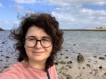 Portrait of smiling woman standing at beach