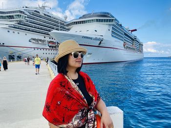 Beautiful woman standing by boat against sea