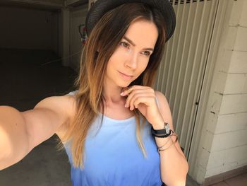 Portrait of smiling young woman standing against wall