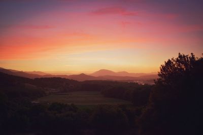 Scenic view of silhouette field against orange sky