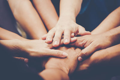 Close-up of stacking hands while huddling outdoors