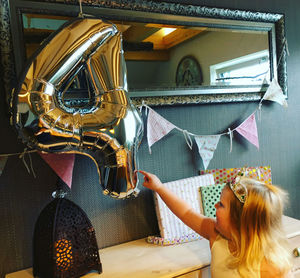 Girl touching number 4 helium balloon during birthday