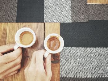 Directly above shot of people holding coffee cup on table