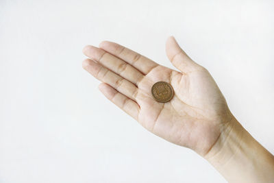 Close-up of hand holding ring against white background