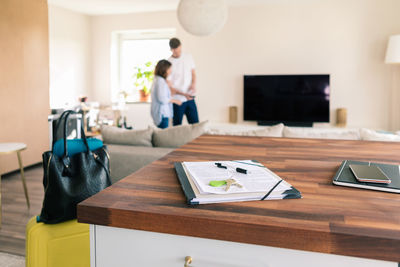 Contract papers and house key on table with landlord and tenant standing in background