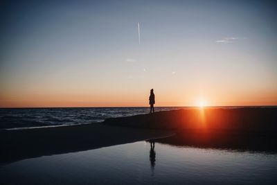 A sunset beach landscape with a woman in the middle and a small lake