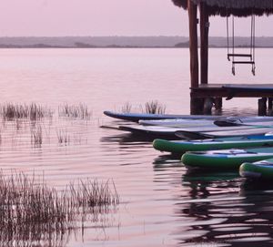 Boats in swimming pool by lake against sky