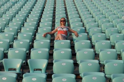 Low angle view of woman sitting on seat at stadium