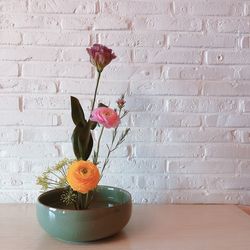 Flower vase on table against wall