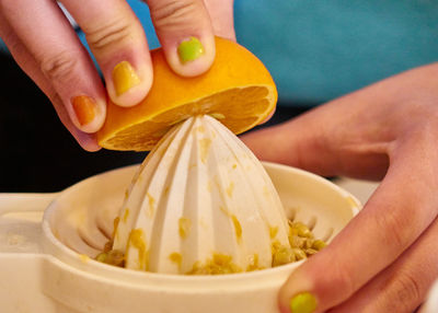 Close-up of hands squeezing an orange 