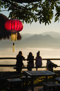 Group of people against calm lake at sunset