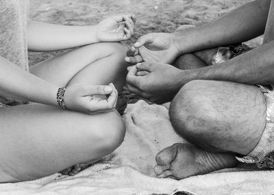 Man holding woman hand during meditation at beach