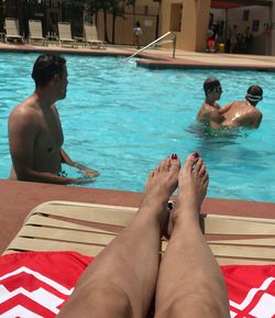 Low section of friends sitting on swimming pool