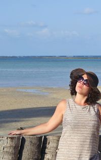 Woman standing by wooden posts at praia dos carneiros against sky