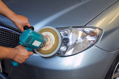 Cropped hands of man polishing car in auto repair shop