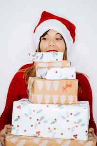 Smiling woman holding christmas gifts while standing against white background