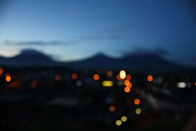 Defocused lights against sky at night