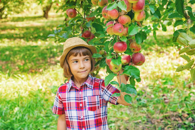 Smiling cute girl standing by apple tree