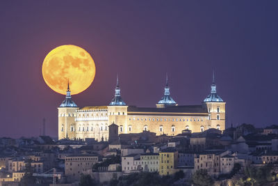 Illuminated buildings against clear sky at night