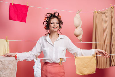 Portrait of a smiling young woman standing against wall