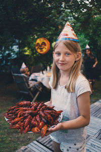 Portrait of girl holding plate of crayfish at garden dinner party