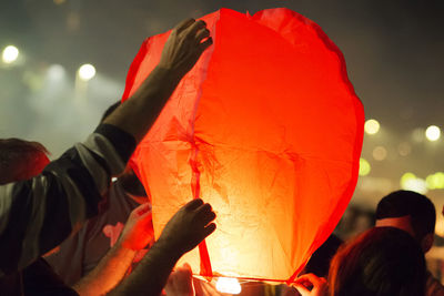 Midsection of people holding red lantern at night