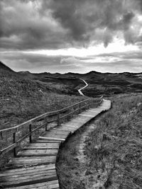 Footpath leading towards mountain against sky