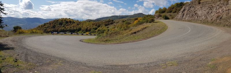 Scenic view of road by mountains against sky