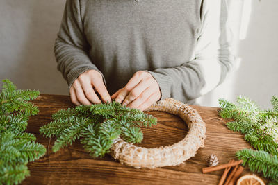 A male florist makes a new year's wreath with fresh fir branches, pine cones and dried fruits.