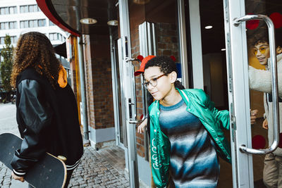 Multiracial male and female friends coming out from building entrance