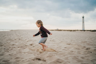 Child boy kid playing a the beach on a cloudy day