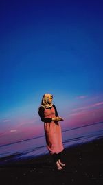 Woman standing at beach during sunset