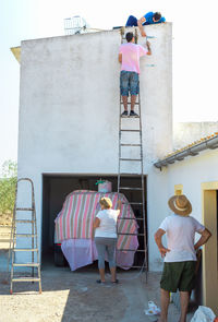 Family install a tv antenna together on the roof of a country house