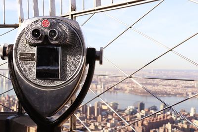 Close-up of modern cityscape and a telescope against sky in new york city 