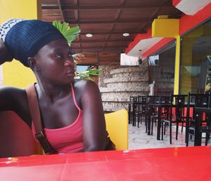 Portrait of teenage girl sitting on chair at restaurant