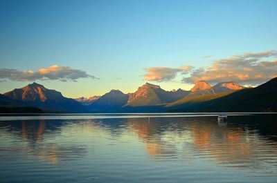 Scenic view of lake by mountains against sky during sunset