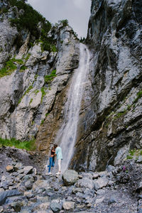 Woman standing on rock against waterfall