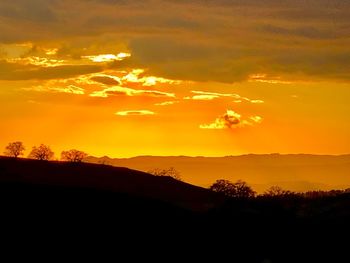 Scenic view of silhouette mountains against orange sky